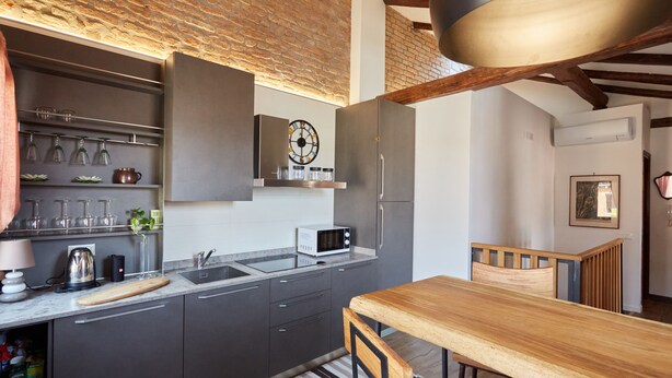 A modern kitchen with grey cabinets, a wooden dining table, and a brick ceiling. - Acqua Susanna - Penthouse with terrace (Venezia)