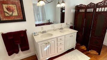 A bathroom with two sinks, a large mirror, a chandelier, and a red towel rack.