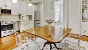 Una cocina moderna con armarios blancos, una mesa de comedor de madera y sillas transparentes.