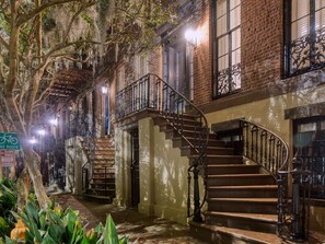 A historic building with a central staircase, brick walls, and a tree-lined courtyard.