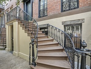 A staircase with ornate black railings and beige steps leading to a door with a window above it. - Gorgeous Designer Apartment, Heated Pool Access (Savannah)