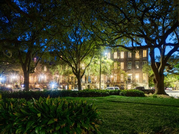 A nighttime view of a building with multiple windows and a well-maintained lawn.
