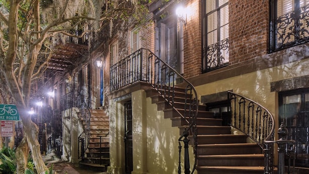 Un edificio histórico con una escalera central, paredes de ladrillo y un patio arbolado.