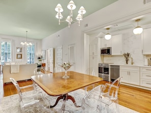 A spacious kitchen with white cabinets, a wooden dining table, and clear chairs. - Gorgeous Designer Apartments, Heated Pool Access (Savannah)