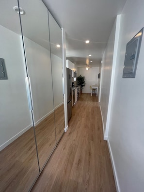 Enter a clean and contemporary space with a compact kitchen area and sliding glass door leading to a room with a mirrored closet.