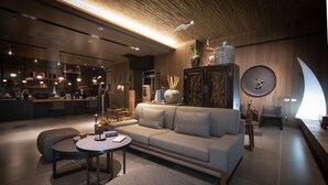 A modern interior with a sofa, round coffee table, and a dining area with a bar. - Hotel Day Plus Sun Moon Lake (Yuchi)