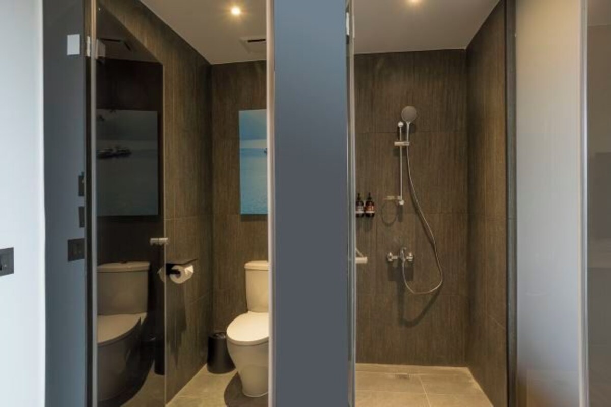A modern bathroom with a glass-enclosed shower, a toilet, and a sink.