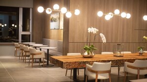 A modern dining area with a long wooden table, white chairs, and a central orchid plant. - Hotel Day Plus Sun Moon Lake (Yuchi)