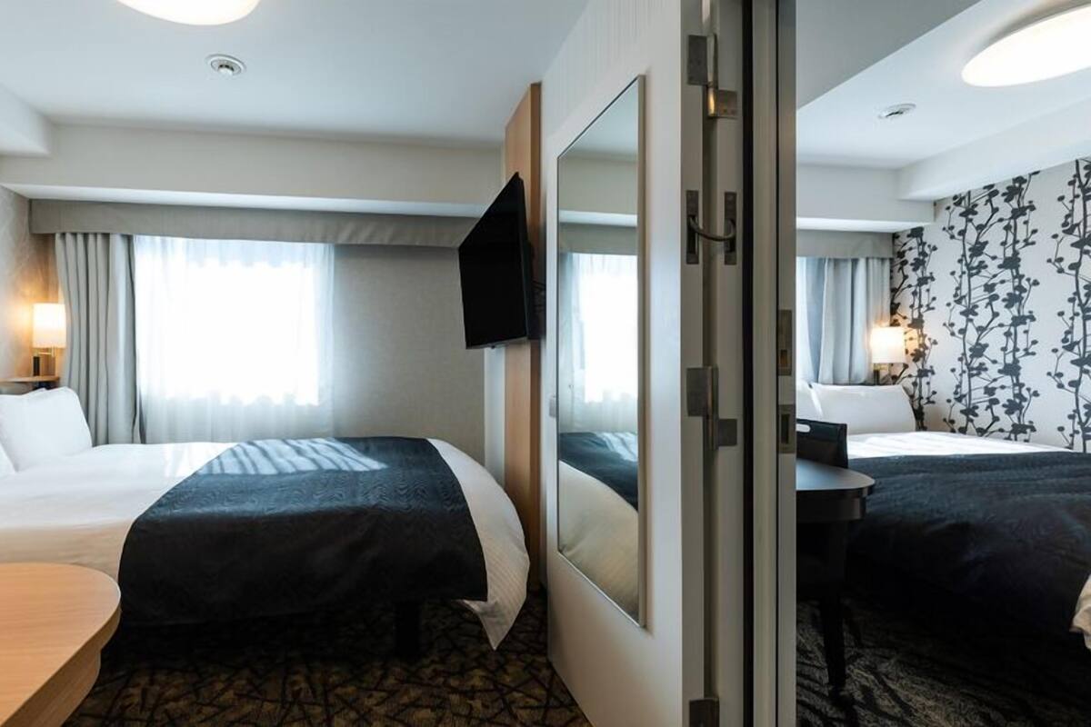 Une chambre d’hôtel avec deux lits, une télévision, un bureau et un miroir.