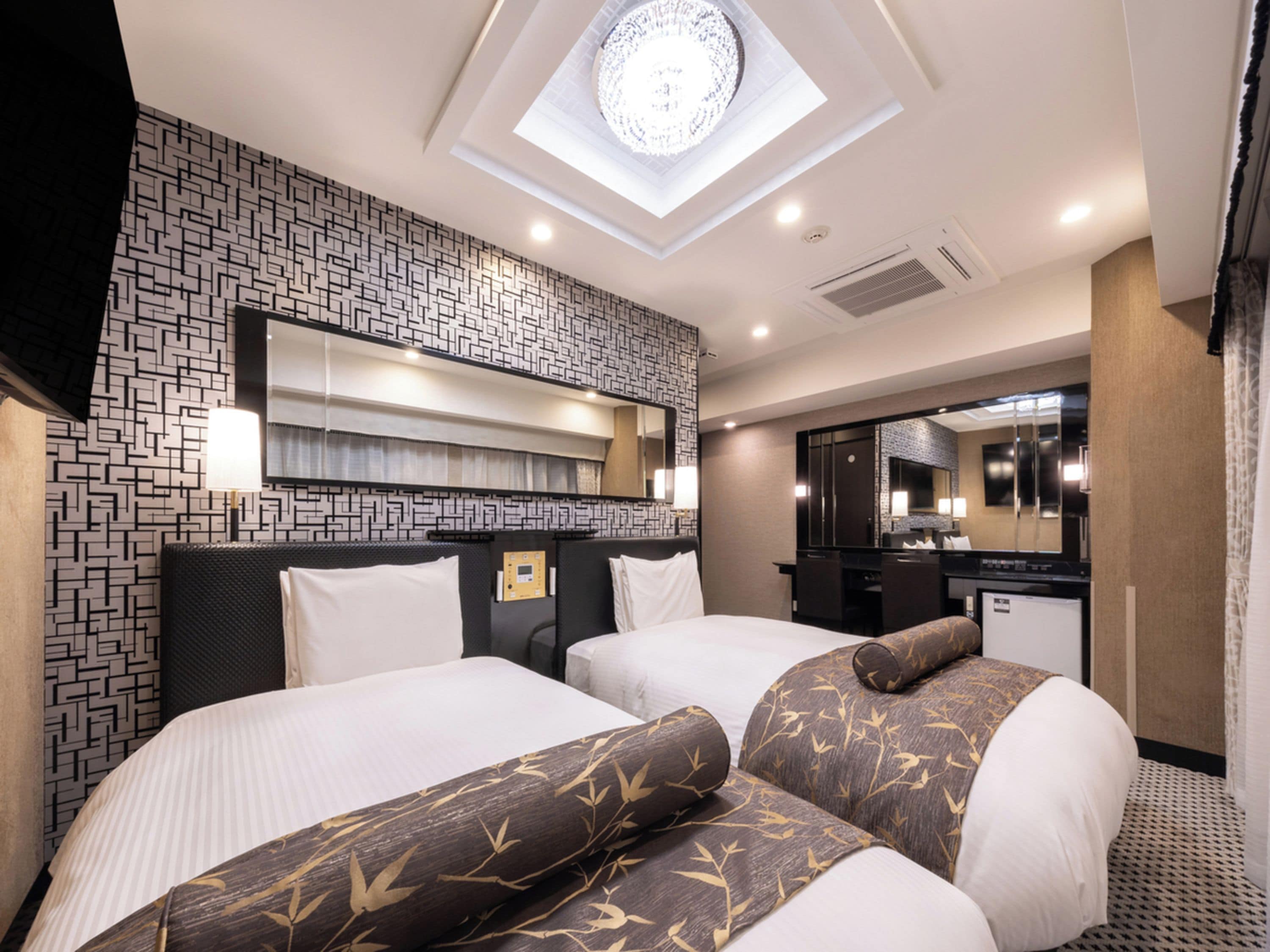 Habitación de hotel con dos camas, un tragaluz, un minibar y un espejo de baño.