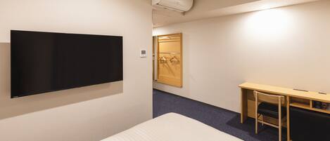 Une chambre d’hôtel comprenant un lit, un bureau, une chaise, une télévision et une armoire.