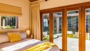A bedroom with a large bed, wooden ceiling beams, a window, and a view of the outdoors.