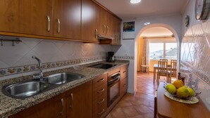 A kitchen with wooden cabinets, granite countertops, a sink, and a coffee maker.