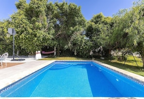 A rectangular swimming pool with a tiled edge, surrounded by a grassy area and trees. - Villa "Manuel" with Mountain View, Sea View, Pool, Terrace & Garden (Nerja)