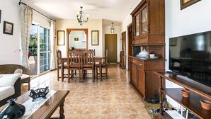 A dining area with a wooden table and chairs, a television, and a cabinet. - Villa "Manuel" with Mountain View, Sea View, Pool, Terrace & Garden (Nerja)