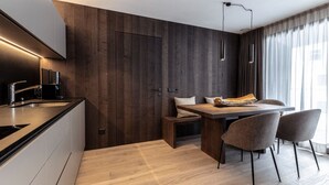 Eine moderne Küche mit einer Holzwand, einem Essbereich mit Tisch und Stühlen sowie einer integrierten Kaffeemaschine.