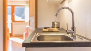 Una cocina moderna con un lavamanos de acero inoxidable, una tabla de cortar de madera y una ventana al fondo.