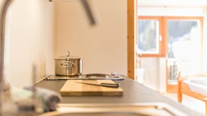 A kitchen with a pot on the stove, a cutting board, and a knife. - Lettnerhof – Family Suite Balcony 5. Surrounded by Nature, South-Facing Balcony, Mountain View, Wi-Fi. (Welsberg)