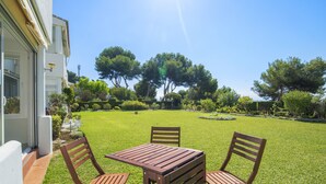 Un patio con tavolo e sedie, un prato curato e alberi sullo sfondo.
