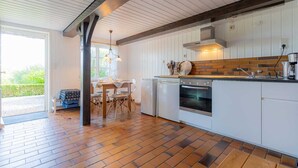 Una cocina moderna con gabinetes blancos, un salpicadero de ladrillo y una mesa de comedor de madera con sillas.