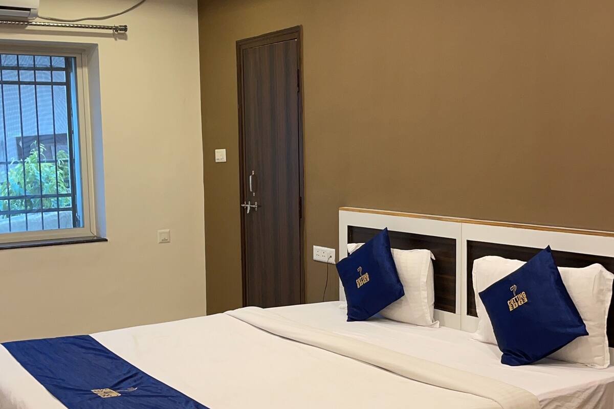 Ein modernes Hotelzimmer mit einem großen Bett, einem Deckenventilator, einer Klimaanlage und einem Fenster mit Blick auf Grünflächen.