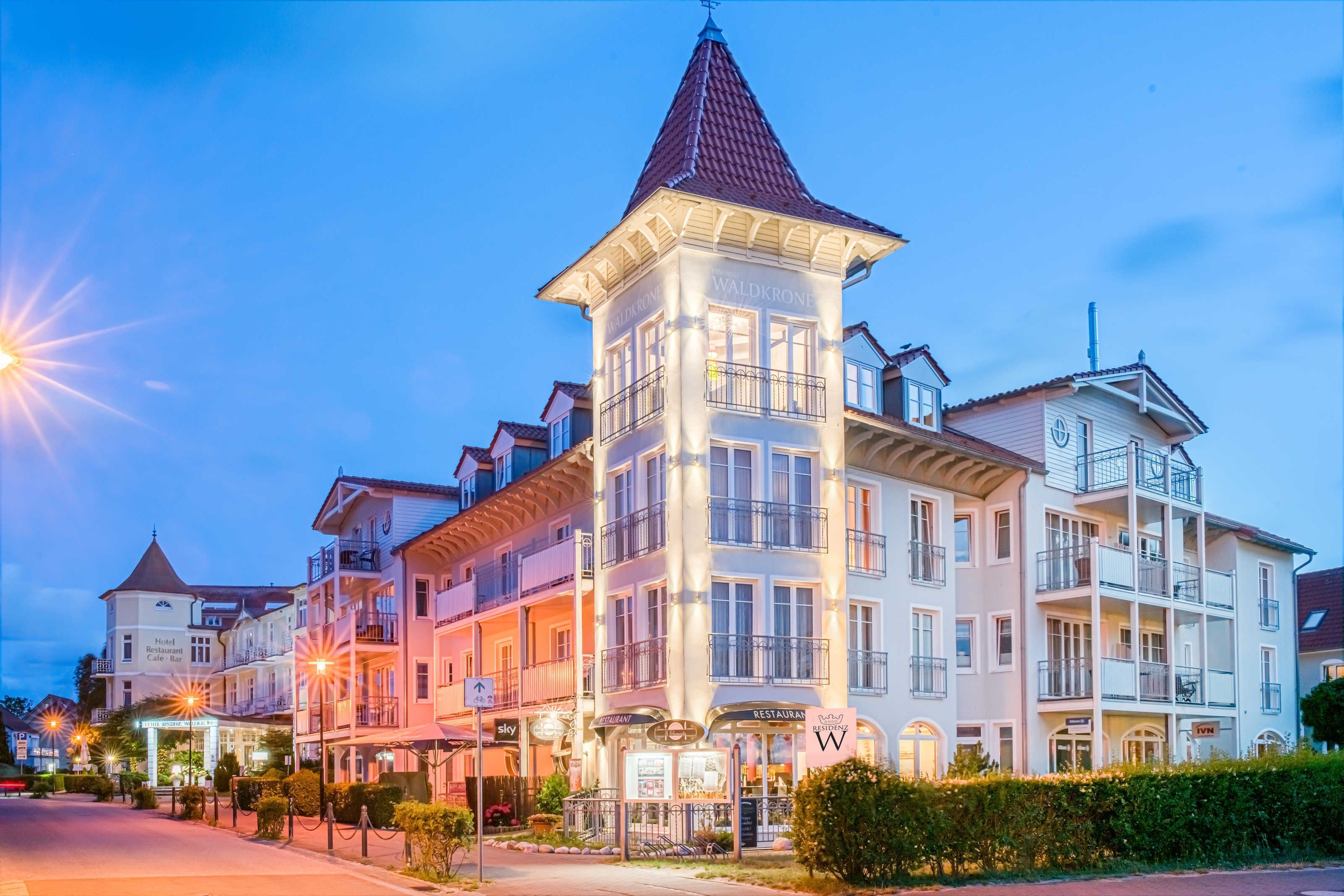 A hotel with a tower, multiple balconies, and signage for a restaurant and cafe.