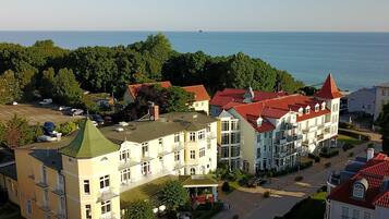 A multi-story hotel with balconies, a courtyard, and a view of the sea.