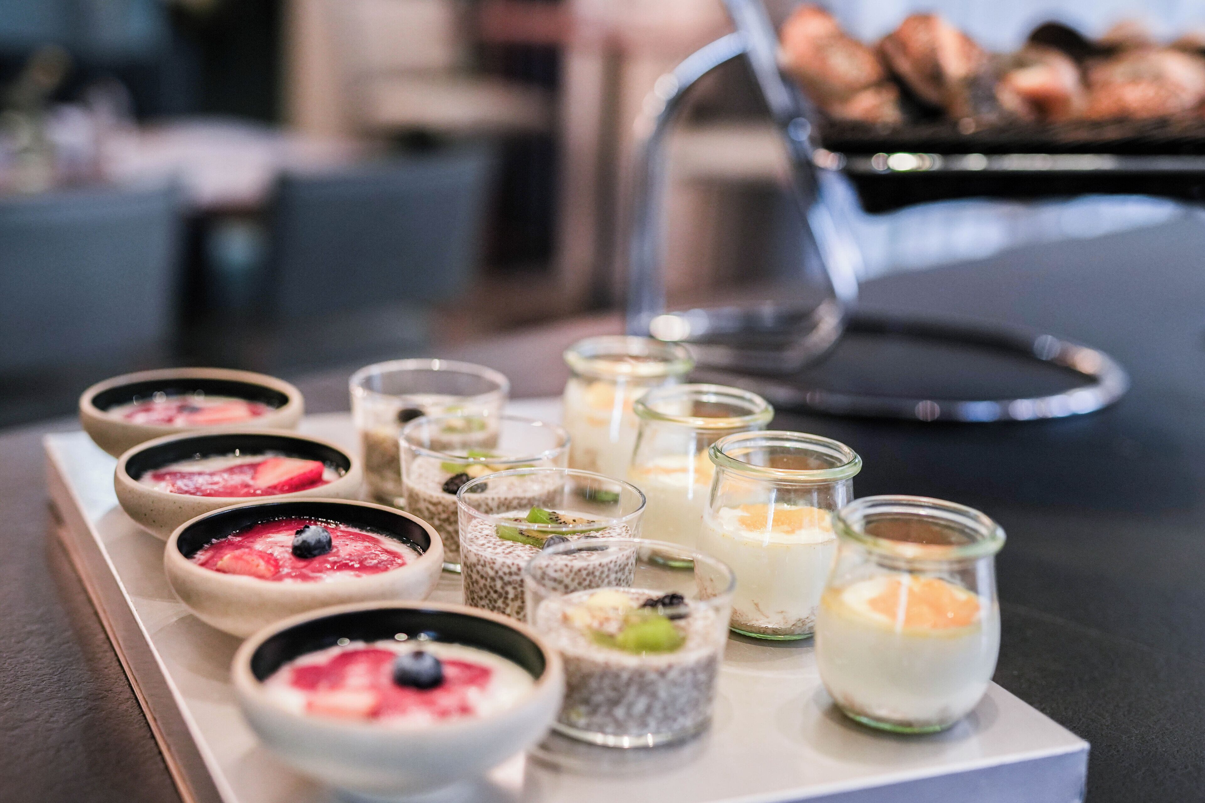 A variety of desserts on a tray, including bowls and small glasses with different toppings.