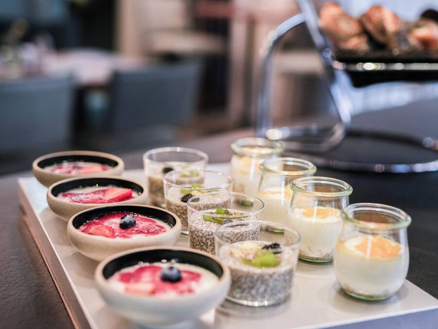 A variety of desserts on a tray, including bowls and small glasses with different toppings.