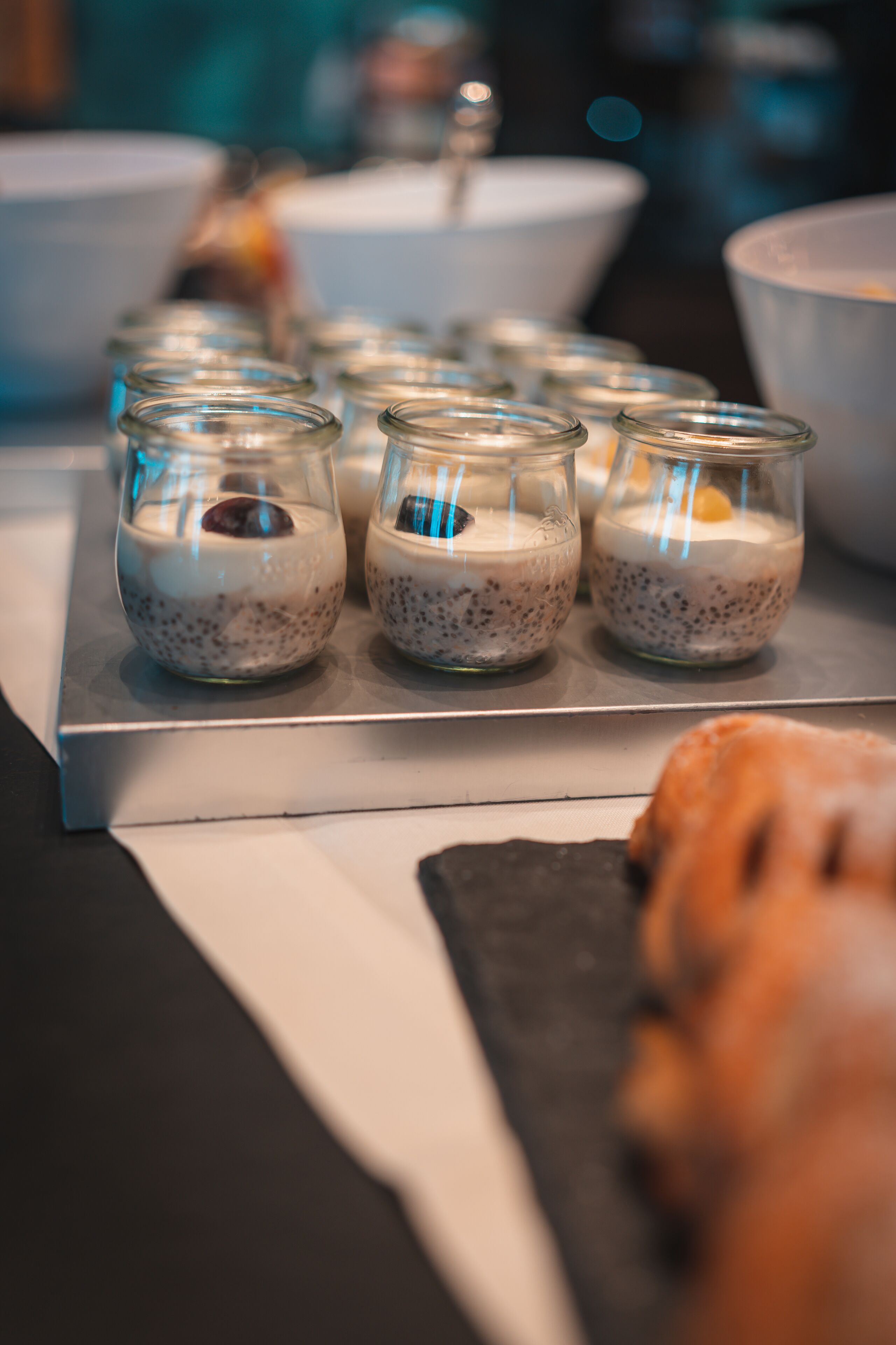 A tray with small glass cups containing a dessert, possibly pudding, with a spoon in each.
