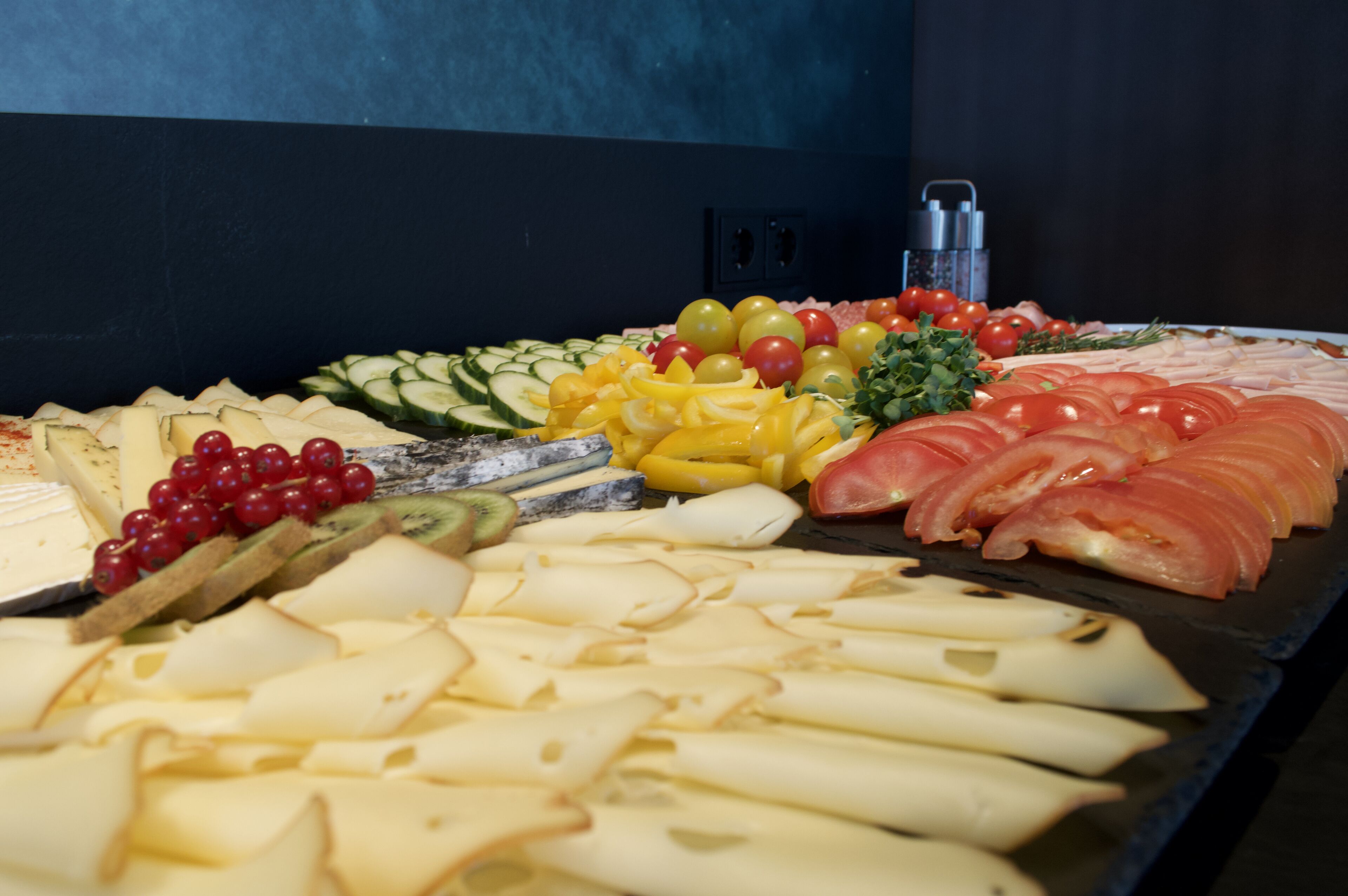 Un tagliere con diversi formaggi, frutta e salumi.