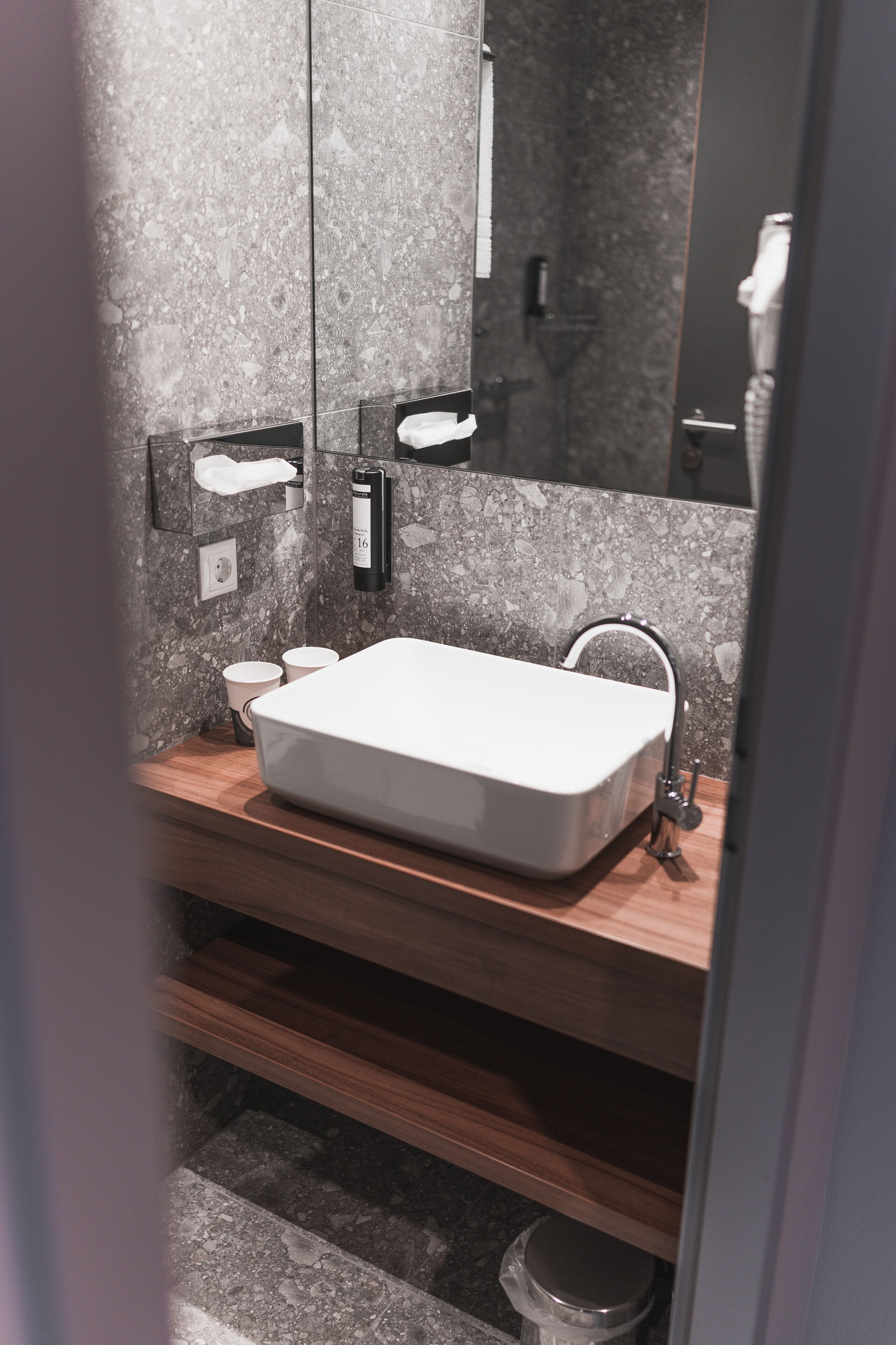 Un baño moderno con un lavabo rectangular, un espejo y un perchero para toallas.