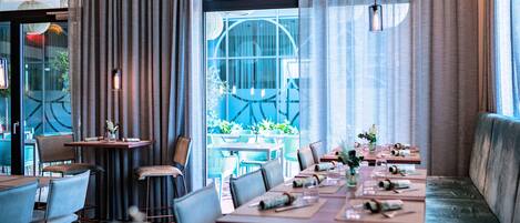 A restaurant with a long table set for dining, a sofa, and a view of the outdoors.