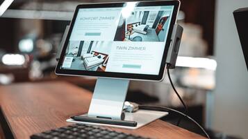 A desktop computer with a monitor displaying a website about a hotel room.