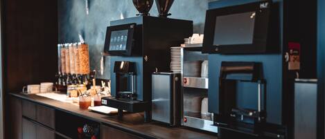 A commercial kitchen with coffee machines, a water dispenser, and a coffee press.