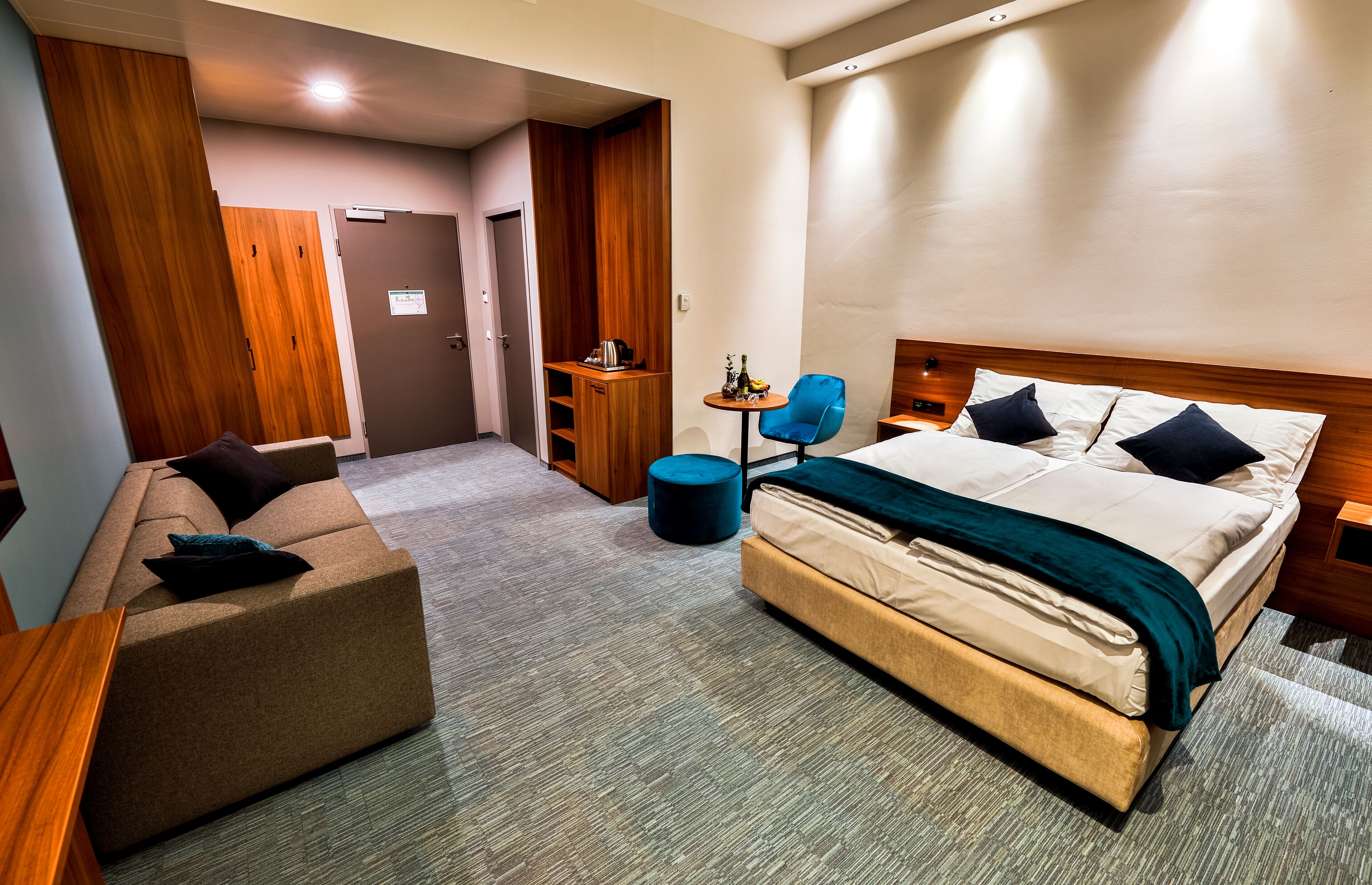 Une chambre d’hôtel avec un lit, un canapé, une petite table et une armoire en bois.