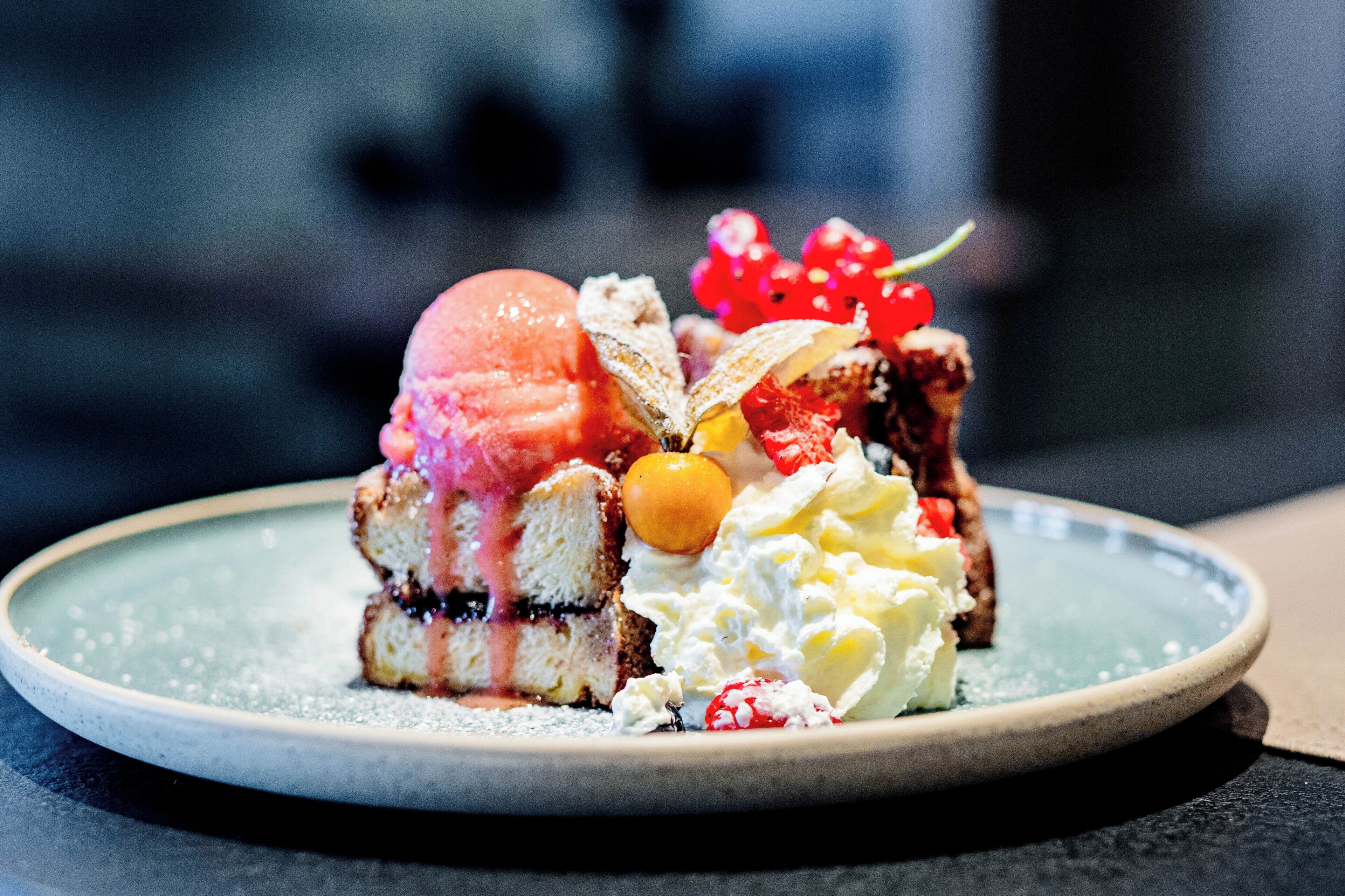 A dessert on a plate with various fruits and whipped cream.