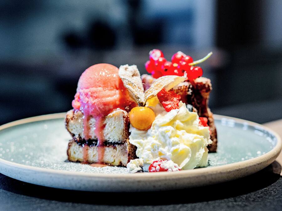 A dessert on a plate with various fruits and whipped cream.