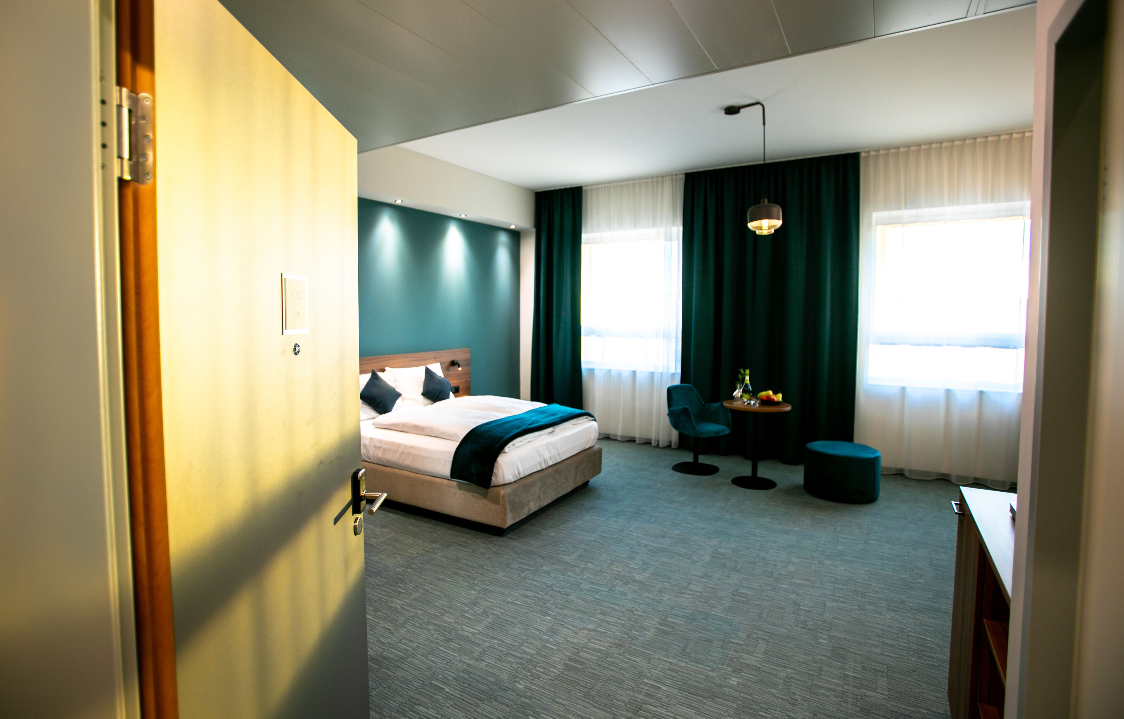 A hotel room with a bed, a desk, a chair, and a small table.