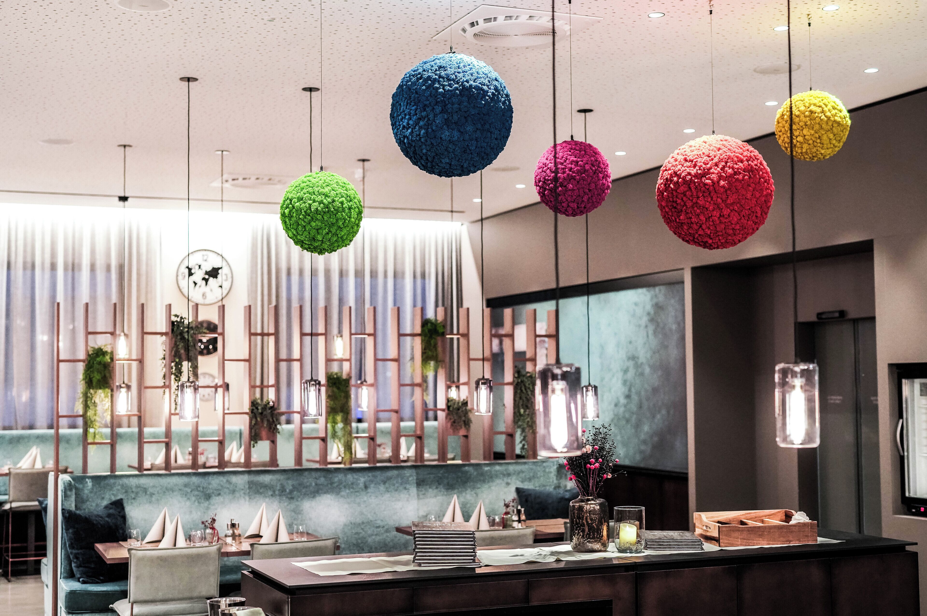 Un interior moderno con una zona de bar, asientos y esferas decorativas colgantes.