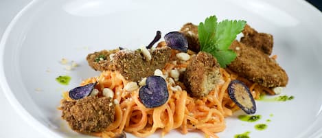 A white plate with pasta, breaded items, and garnishes.