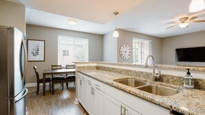 A modern kitchen with granite countertops, stainless steel appliances, and a dining area with a table and chairs. - Overlook Downtown GVL! (Greenville)