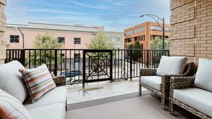 A balcony with wicker furniture and a view of buildings in the background. - Overlook Downtown GVL! (Greenville)