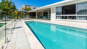 A modern swimming pool with a clear blue water, surrounded by a tiled deck and lounge chairs. - Paradise on the Promontory (BANKSIA BEACH)
