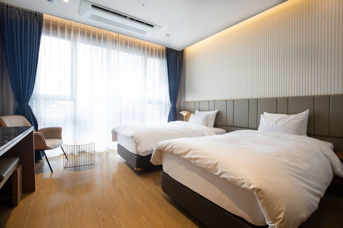 Habitación de hotel con dos camas, un escritorio y una silla.