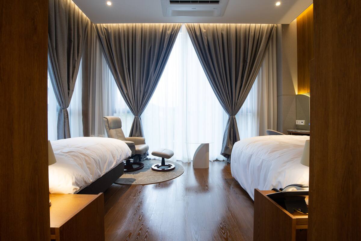 Habitación de hotel con dos camas, un escritorio, una silla y una mesita.