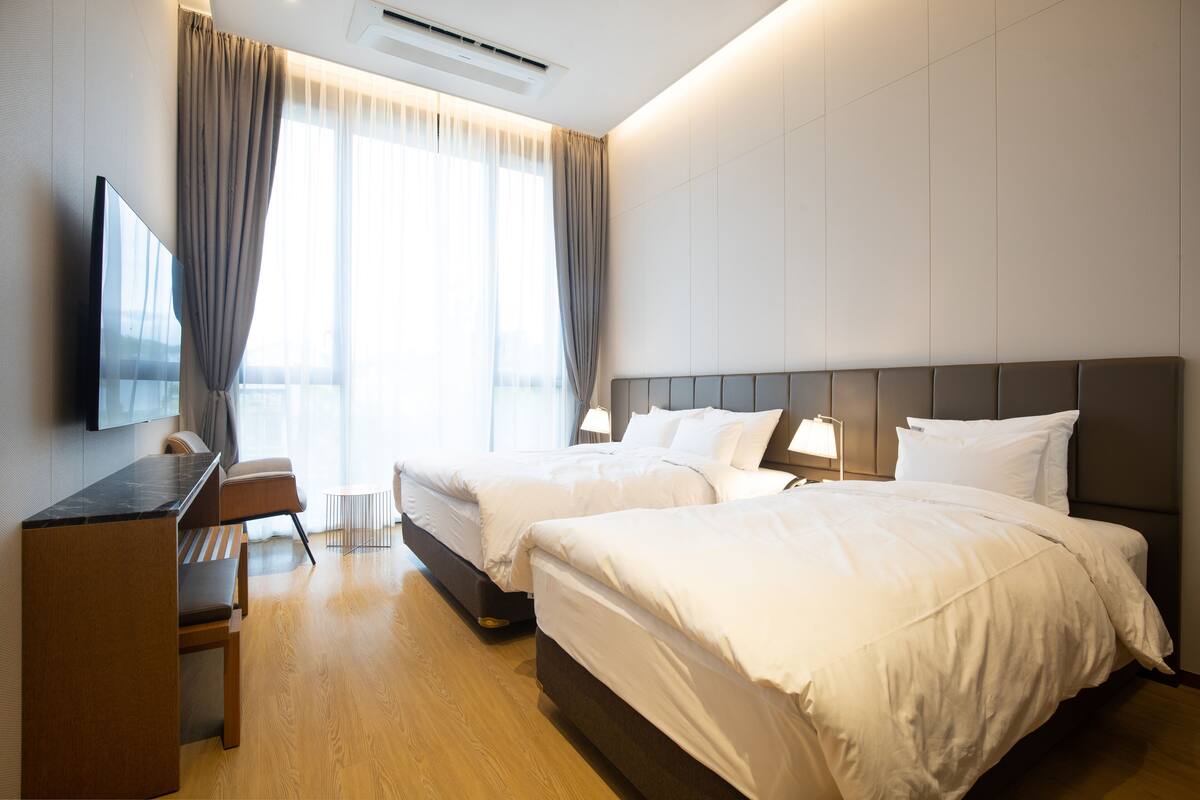 Una habitación de hotel con dos camas, un escritorio, una silla y un televisor.