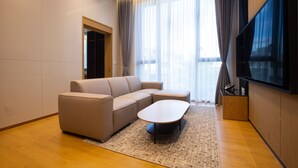 Een moderne woonkamer met een hoekbank, een salontafel en een flatscreen tv aan de muur.