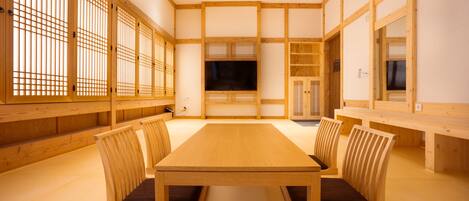 Ein traditioneller japanischer Raum mit Tatami-Böden, einem niedrigen Holztisch und fest eingebauten Sitzmöglichkeiten.