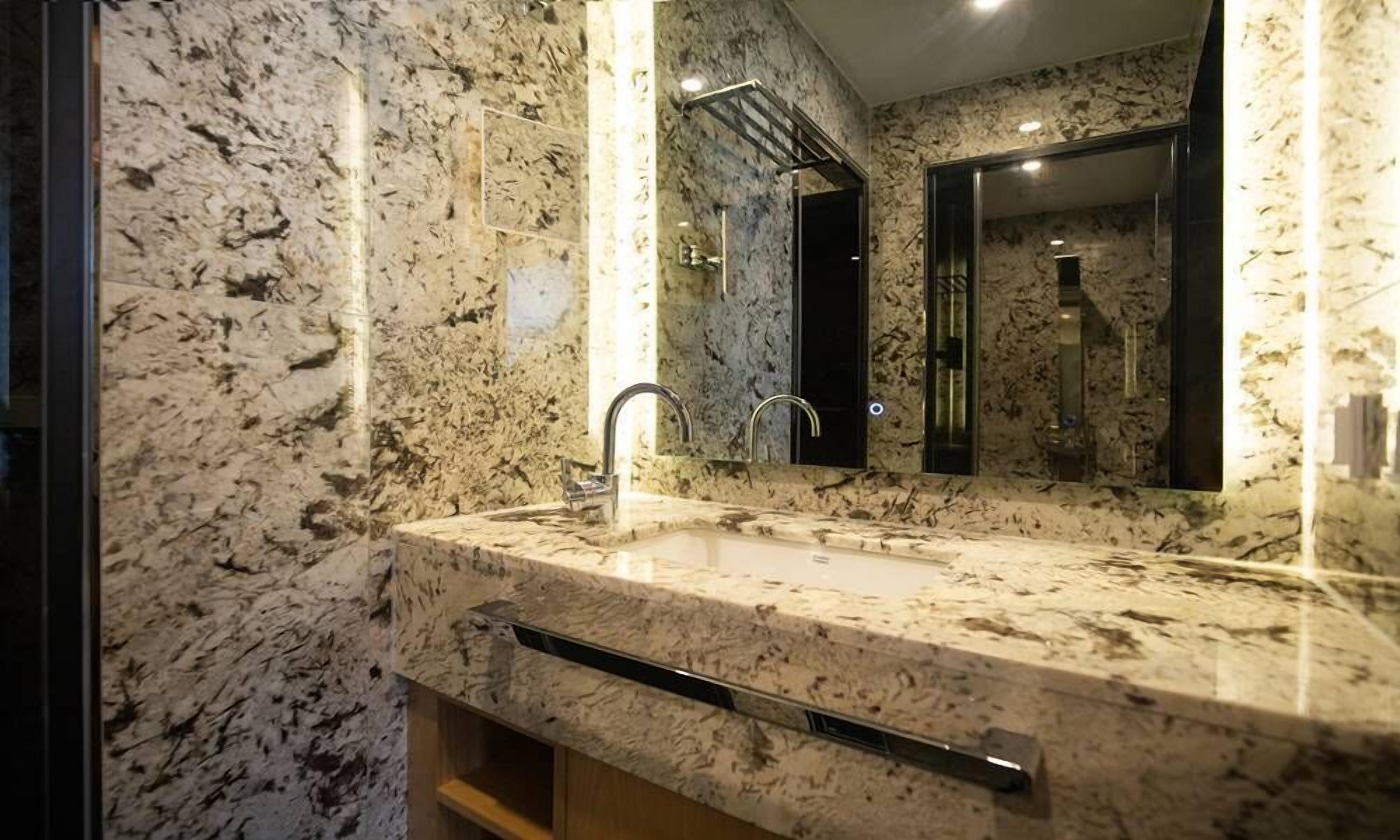 A bathroom with a marble sink, a mirror, and a towel rack.